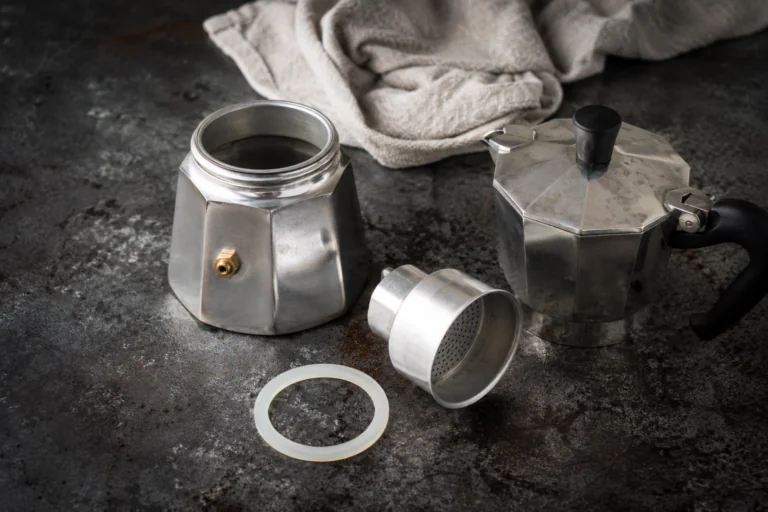 Cafetière moka démontée sur un plan de travail avec chiffon doux