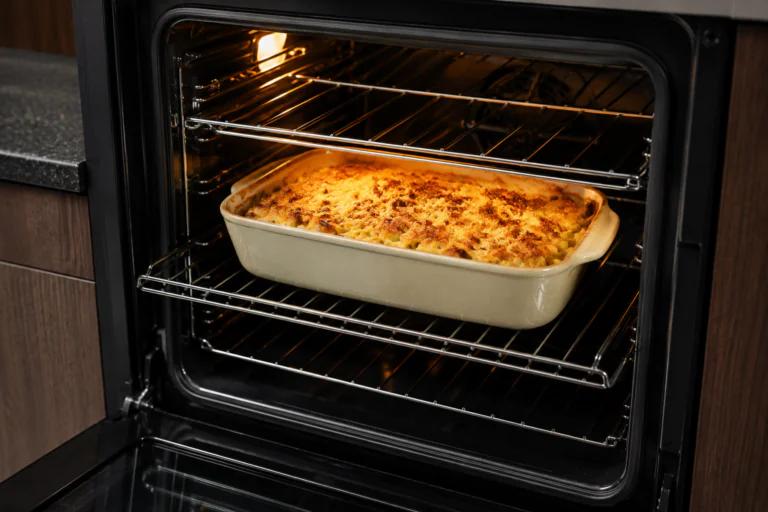 Plat à gratin placé au centre d'un four ouvert avec plusieurs niveaux de grille visibles