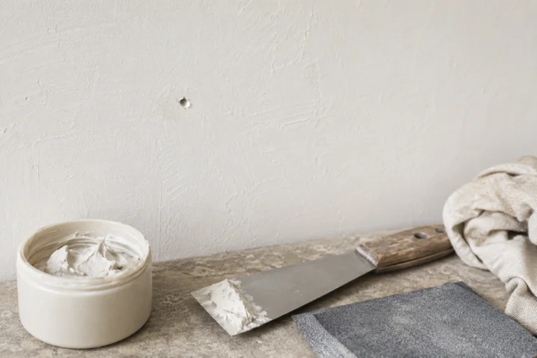Petit trou dans un mur peint avec enduit et outils de réparation