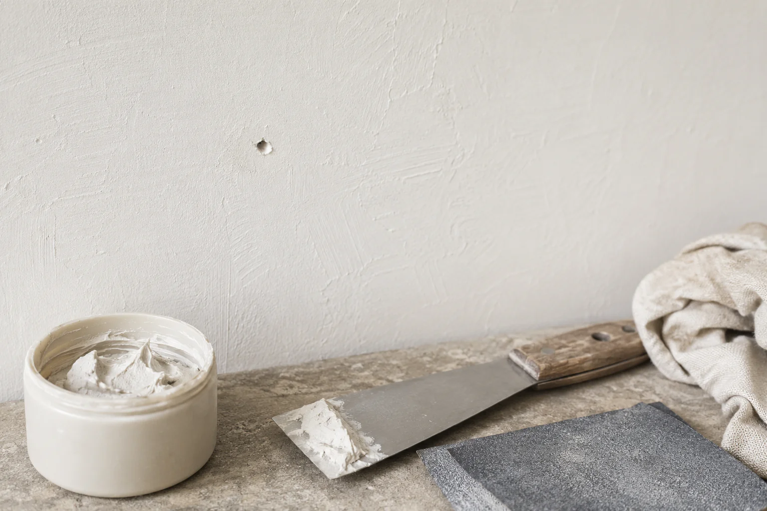Petit trou dans un mur peint avec enduit et outils de réparation