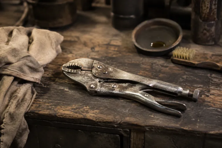 Pince métallique légèrement rouillée sur un établi avec brosse et chiffon
